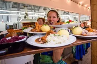 Wiesn Bedienung auf dem Oktoberfest mit bayerischen Schmankerln wie Knödel, Blaukraut und Schweinshaxen - die Klassiker. Wiesn Bedienung auf dem Oktoberfest mit bayerischen Schmankerln wie Knödel, Blaukraut und Schweinshaxen - die Klassiker.