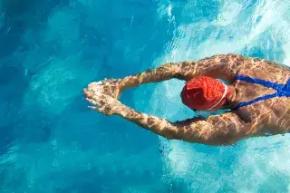 20200809_schwimmerin-im-schwimmbad-T-Design Shutterstock Eine Schwimmerin im Hallenbad zieht ihre Bahnen