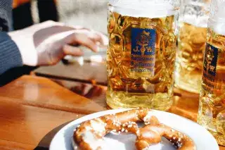 Biergarten-Gäste sitzen am Tisch mit Masskrug und Brezn