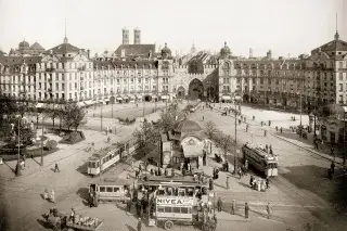 Historische Aufnahme: Die Ostseite des Karlsplatzes mit dem nach Plänen Gabriel von Seidls 1899 bis 1902 neubarock gestalteten Rondell, 1913. Der doppelstöckige Motoromnibus in Vordergrund gehörte zu einem privaten Unternehmen, das eine Linie zwischen dem Karlsplatz und Neuhausen betrieb.