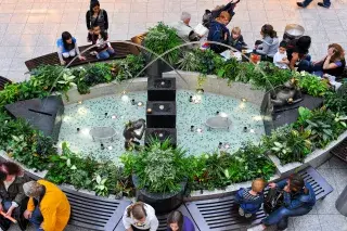 Menschen sitzen auf Bänken am Froschbrunnen im Olympia-Einkaufszentrum.