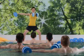 Aquafitness Trainerin leitet Teilnehmer im Schwimmbecken.