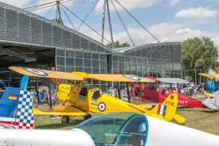 Ein Doppeldecker und weitere Flugzeuge vor der Flugwerft Schleißheim