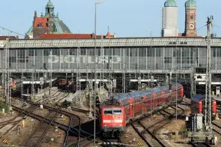 20210809_Hauptbahnhof Eine rote Lok mit einem Regionalexpress fährt auf den Gleisen aus der Haupthalle des Münchner Hauptbahnhofs