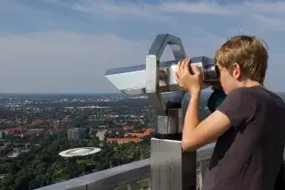 Ein Junge schaut durch ein Fernglas auf der Aussichtsplattform des Olympiaturms