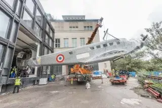 Ein Kran und mehrere Mitarbeiter heben das Flugzeug "Tante Ju" aus dem Deutschen Museum.