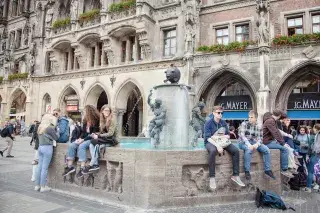 Eine Gruppe junger Leute erfrischt sich am Fischbrunnen