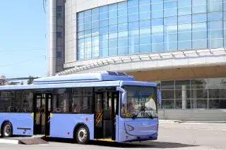 Der DB Oberbayernbus steht vor einem Firmengebäude.