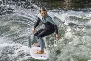 Eine Surferin reitet die Eisbachwelle