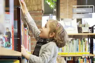 Ein Kind greift nach einem Buch in der Münchner Stadtbibliothek im Gasteig