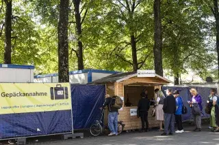 Besucher der Wiesn geben ihr Gepäck bei der Gepäckaufbewahrung ab Besucher der Wiesn geben ihr Gepäck bei der Gepäckaufbewahrung ab
