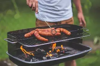 Ein Mann grillt Würstchen