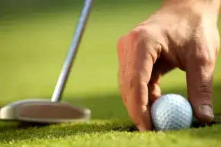 Eine Hand greift nach einem Golfball