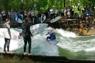 Eine Surferin reitet die Eisbachwelle im Lehel Eine Surferin reitet die Eisbachwelle im Lehel