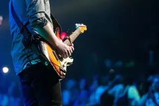 Musiker mit E-Gitarre bei einem Konzert auf der Bühne