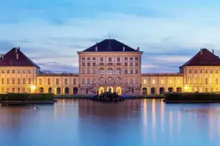 Schloss Nymphenburg leuchtet in der Abenddämmerung Schloss Nymphenburg leuchtet in der Abenddämmerung