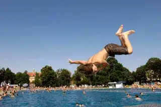 Ein Junge springt vom Startblock ins Schwimmerbecken des Schyrenbads Ein Junge springt vom Startblock ins Schwimmerbecken des Schyrenbads