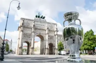 The European Championship trophy stands in front of the Munich Victory Gate in sunny weather