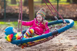 Kinder schaukeln auf Spielplatz