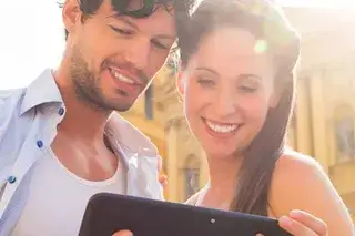 Ein Mann und eine Frau stehen vor der Theatinerkirche und schauen auf ein Tablet Ein Mann und eine Frau stehen vor der Theatinerkirche und schauen auf ein Tablet
