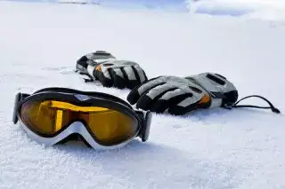 Skibrille und Handschuhe auf Schnee