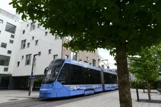 Eine Tram Avenio fährt an der Hochschule entlang