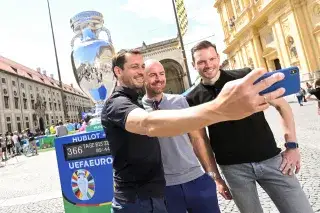 Drei Männer machen ein Selfie mit der großen Kopie des EM-Pokals am Odeonsplatz in München