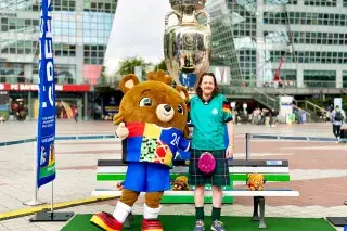 EM-Maskottchen Albärt und ein Fan mit Deutschland-Trikot und schottischem Kilt an einer EM-Bank am Flughafen München EM-Maskottchen Albärt und ein Fan mit Deutschland-Trikot und schottischem Kilt an einer EM-Bank am Flughafen München