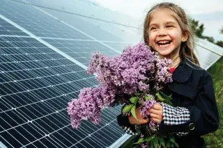 Mädchen mit Blumen vor einer Photovoltaik-Anlage