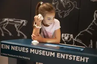 Mädchen hört in Ohrhörer im Biotopia Lab Mädchen hört in Ohrhörer im Biotopia Lab