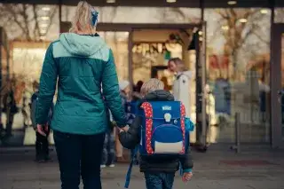 Mutter und junger Schüler auf dem Weg in eine Schule