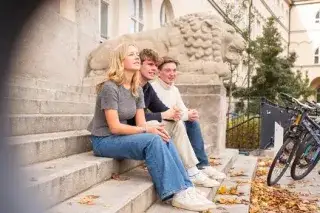Schüler*innen sitzen vor dem Maximiliansgymnasium