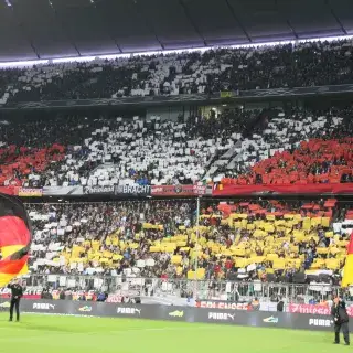 Fans der deutschen Nationalmannschaft bei einem Spiel in der Münchner Fußball Arena bilden eine Choreographie in den Landesfarben Schwarz, Rot und Gold.