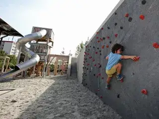 Kind spielt an einer Kletterwand im Spielplatz im Heckenstallerpark.