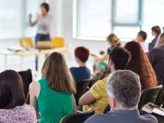 Erwachsene lauschen einem Weiterbildungsseminar