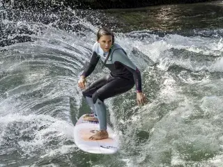 Eine Surferin reitet die Eisbachwelle