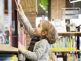 Ein Kind greift nach einem Buch in der Münchner Stadtbibliothek im Gasteig
