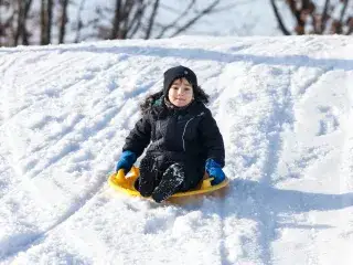 Ein Kind rodelt einen Berg hinunter
