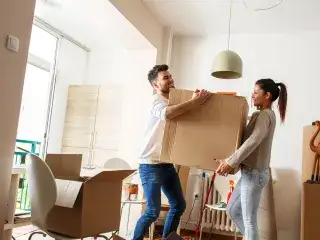 Ein Mann und eine Frau tragen einen Umzugskarton