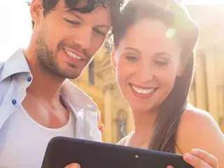 Ein Mann und eine Frau stehen vor der Theatinerkirche und schauen auf ein Tablet