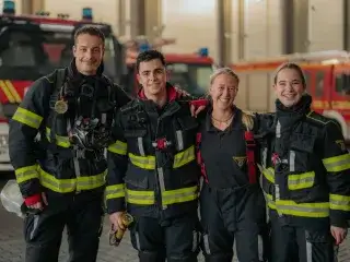 Vier Feuerwehr-Einsatzkräfte lächeln in die Kamera