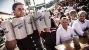 Bedienung trägt Steinkrüge mit Bier auf der Oidn Wiesn