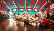 Zwei Frauen in Tracht versuchen beim Fahrgeschäft Teufelsrad auf dem Oktoberfest nicht wegzurutschen. 