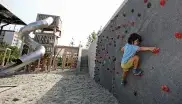 Kind spielt an einer Kletterwand im Spielplatz im Heckenstallerpark.