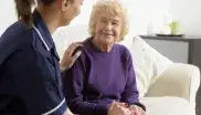 Eine Altenpflegerin kümmert sich um eine ältere Frau