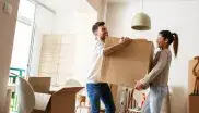 Ein Mann und eine Frau tragen einen Umzugskarton