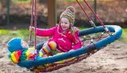 Kinder schaukeln auf Spielplatz