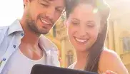 Ein Mann und eine Frau stehen vor der Theatinerkirche und schauen auf ein Tablet