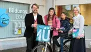 Die ehemalige Bürgermeisterin Katrin Habenschaden und Sportreferent Florian Kraus posieren mit zwei Kindern und einem Fahrrad bei der Übergabe der Upcycling-Materialien.